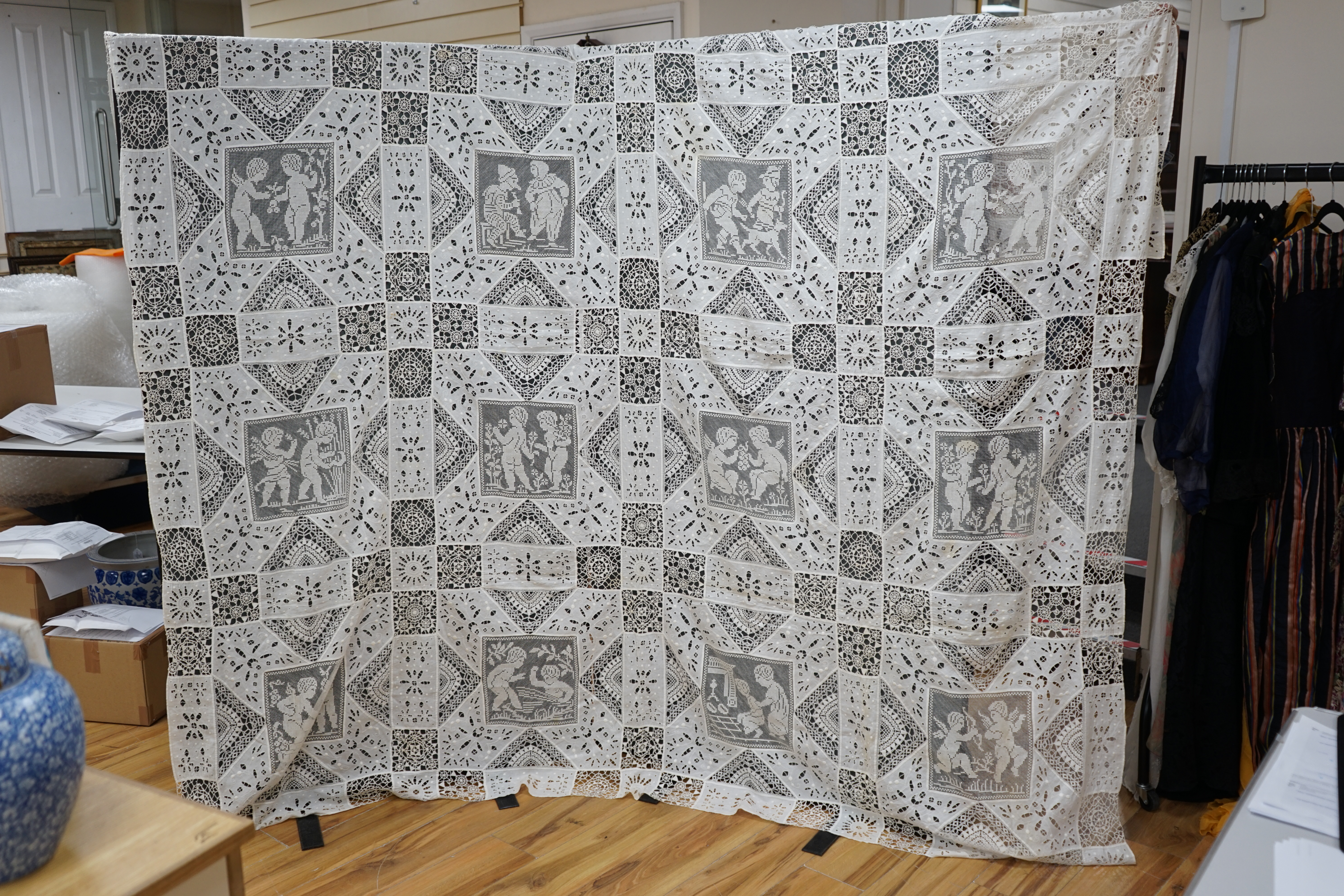 An early 20th century Italian ornate bedcover, worked with square fillet lace insertions of putti, white multi patterned cut work squares on fine linen and similar multi patterned needle lace squares, creating a unique b